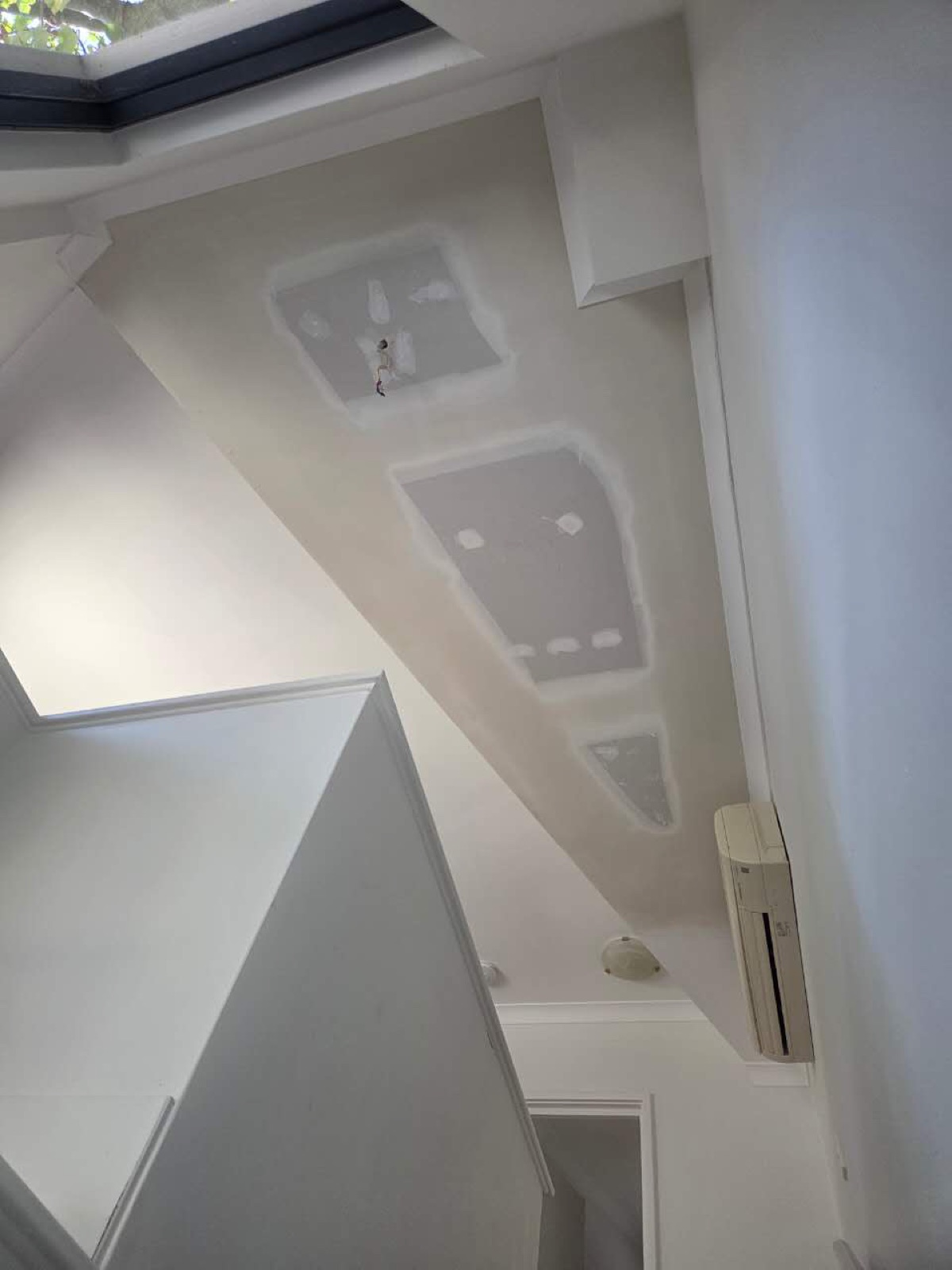 Ceiling after water-damage repair with fresh plasterboard patches and compound ready for paint, Perth